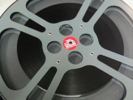 Gray 16mm film reel with film wound onto it