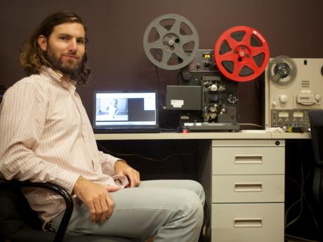 Media archivist and conservator seated at computer terminal